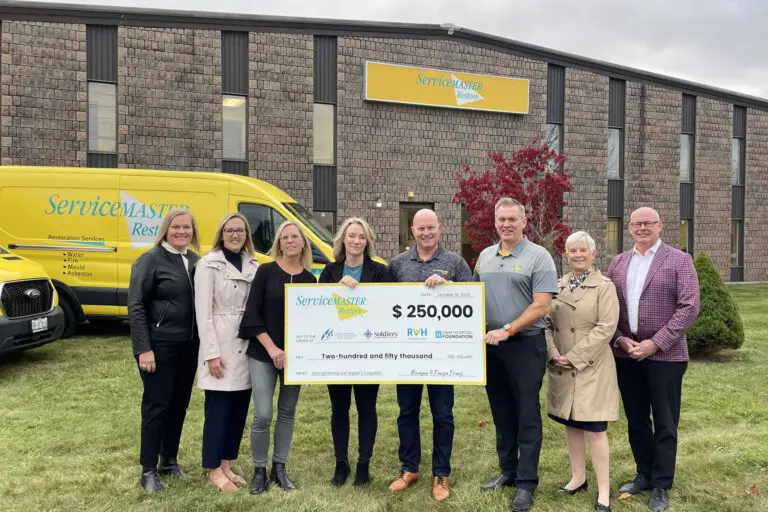 Five women and Three men stand in front of a yellow Service Master Truck holding a huge cheque for $250,000 for Orillia Soldiers' Memorial Hospital
