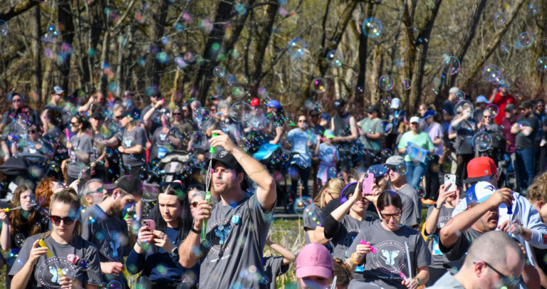 A crowd of people blowing bubbles in the air.