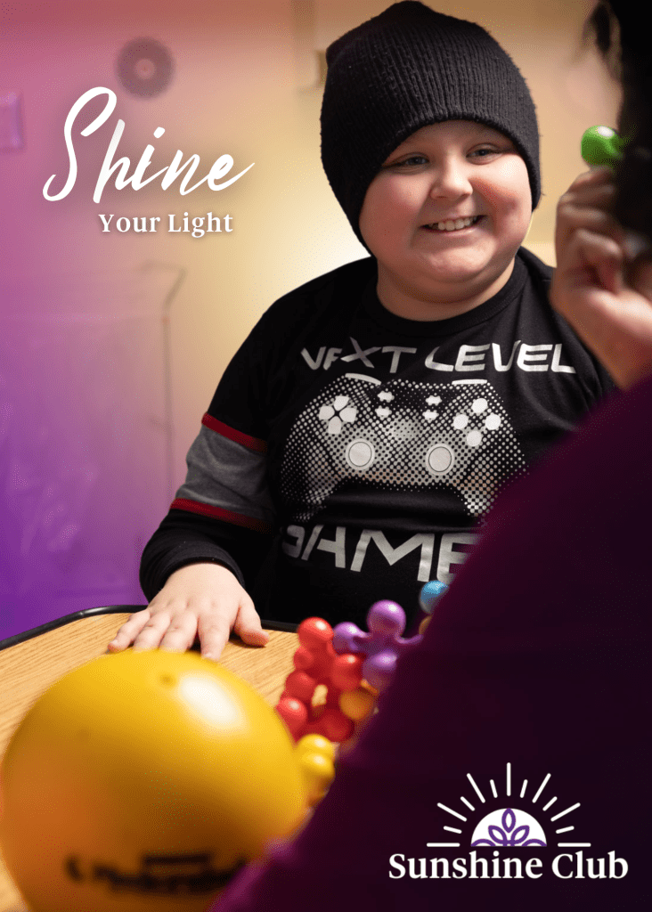 a little boy smiles while doing recreation activities with a healthcare professional at the hospital. The image says "Shine Your Light" and has a logo for Sunshine Club on it.