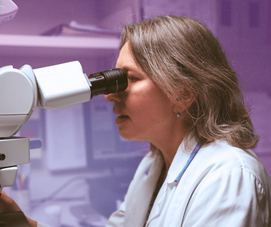 Woman in lab coat looking through a microscope