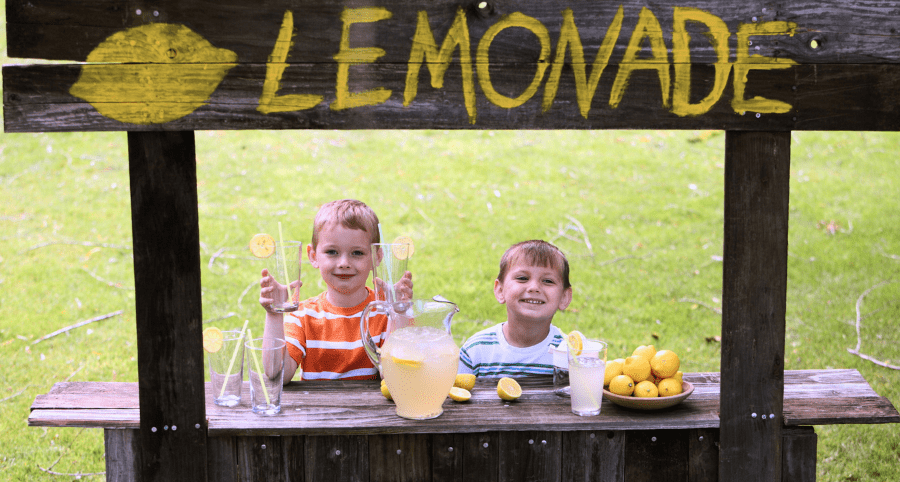 Two little boys sitting at a lemonade stand