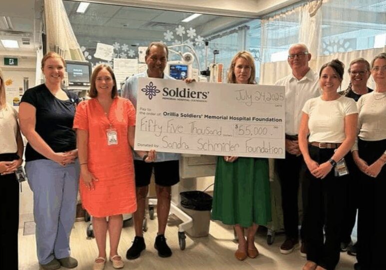 A group of female nurses stand in a Neonatal Intensive Care Unit with a large cheque.